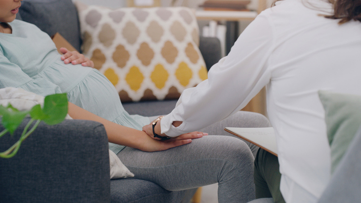 pregnant woman, consulting and nurse on sofa in medical health center. Young female, new mother support and surgery healthcare insurance worker communication with patient or pregnancy treatment care